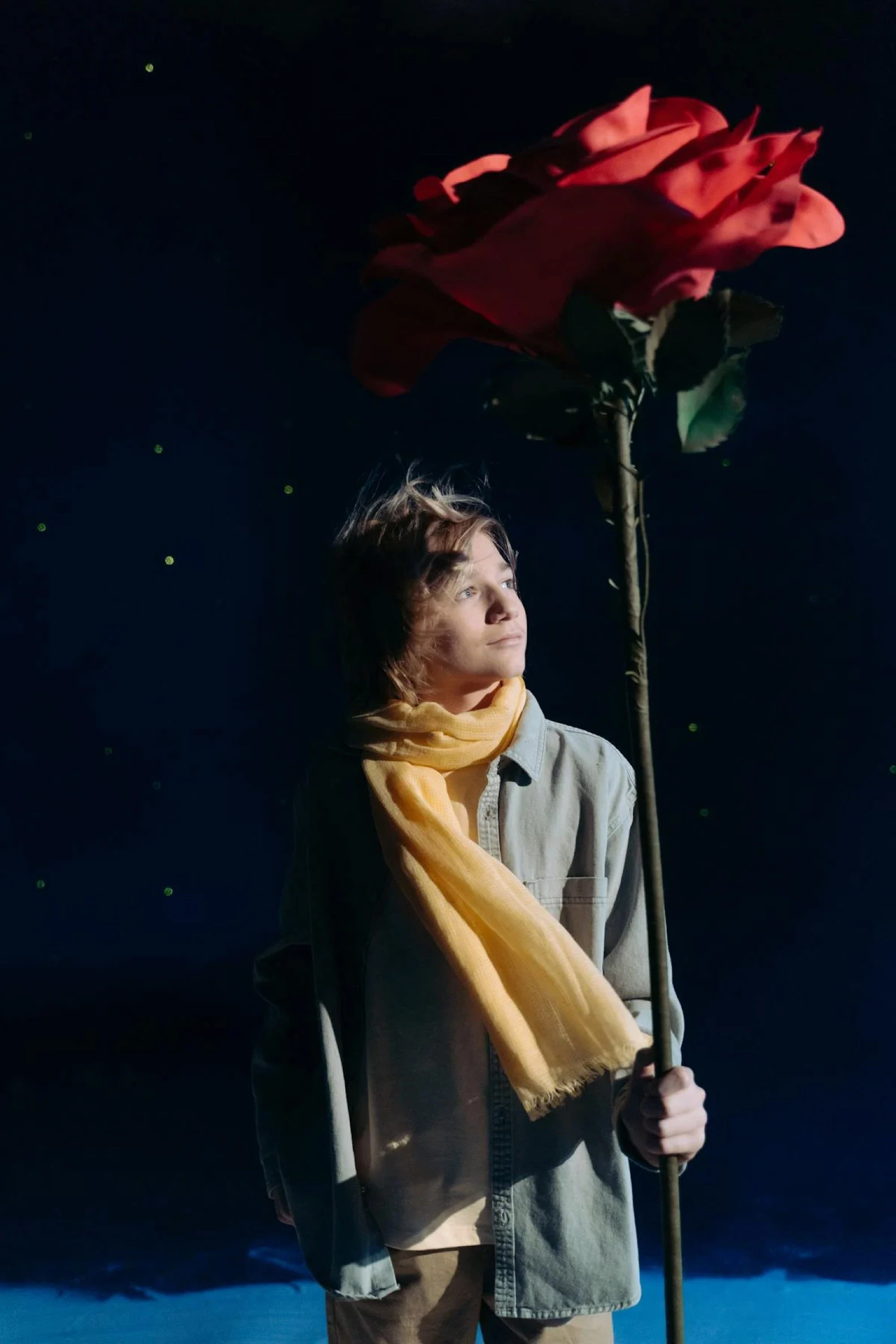 boy-with-yellow-scarf-holding-a-red-flower-7182065